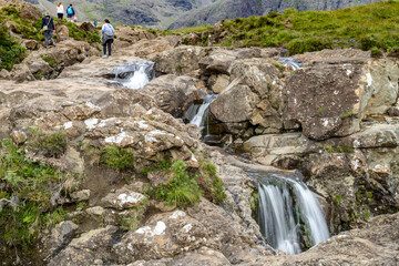 People hike and clamber the rocky pathways of the Fairy Pools,of the Scottish Highlands.