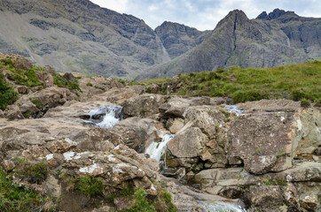 Fototapeta na wymiar People hike and clamber the rocky pathways of the Fairy Pools,of the Scottish Highlands.