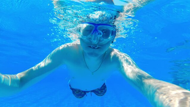 Swimming pool concept. Caucasian male swimmer in special glasses relaxing in hotel swimming pool. Underwater shot. . High quality 4k footage