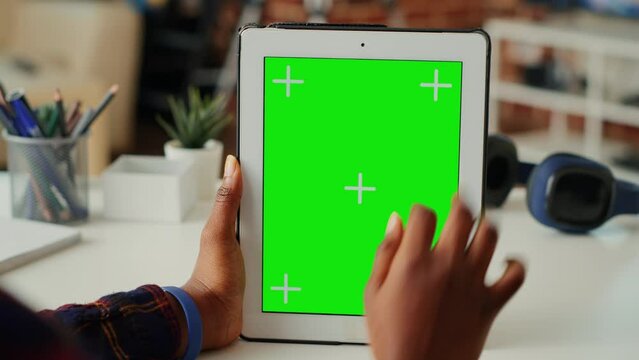 African american woman vertically holding isolated greenscreen on digital tablet, looking at blank chroma key display with mockup background. Using copy space on portable device. Close up.