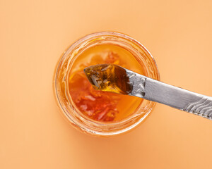 yellow cannabis wax in glass container, golden thc dab