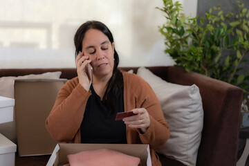 a lady talking by her cell phone with a credit card in her hand.
