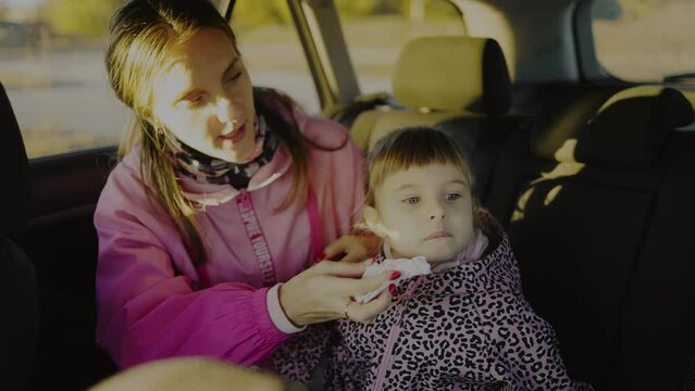 Little girl is sitting in a car with her mom after eating something