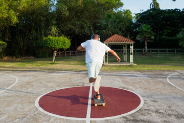 Back view of skateboarder in headphones pushing skateboard on park. © Andrei