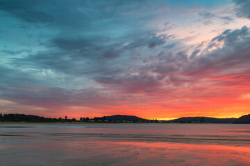 Fototapeta na wymiar Colourful cloud filled sunrise at the seaside