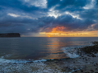 Drizzly moody sunrise seascape with cloud filled sky