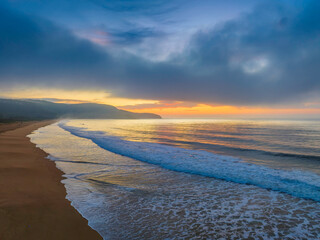 Peaceful sunrise over the ocean with small waves and clouds