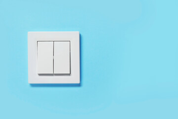 Modern plastic light switch on blue wall, space for text
