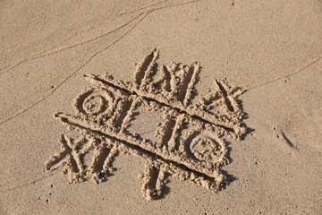 Fototapeta premium Tic tac toe game drawn on sandy beach, above view