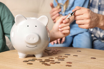 Obraz na płótnie Canvas Family with money and piggy bank at home, closeup
