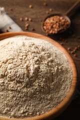 Bowl of buckwheat flour on wooden table, closeup