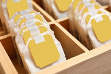 Paper tea bags with tags in wooden box , closeup