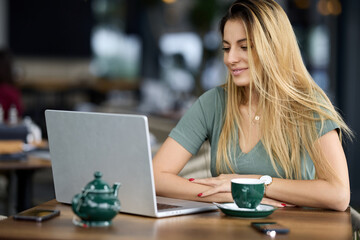 A woman sits in a coffee shop and follows online course.