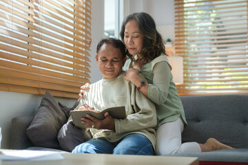 Happy elderly couple relaxing together on comfortable couch at home. Elderly love, family, retirement lifestyle concept.