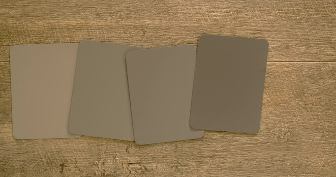 Stop motion time lapse, looping video. Generic color sample swatches in shades of gray through to black. Drab color scheme. Interior design color pallet and inspiration. Wooden background