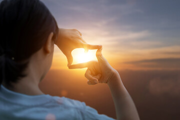 Child girl making frame around the sun with her hands capturing in the sunrise. Planning and vision...