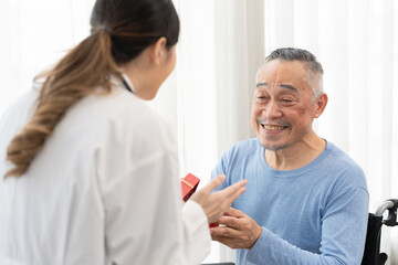 Obraz premium senior man receives a gift box from asian female doctor for happy birthday.