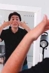 High quality photography. Man in front of the mirror removing the cream from his face. Man taking care of his skin with cream.