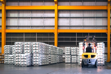 Forklift lifting cargo inside distribution warehouse. Aluminum cargo handling storage, and...