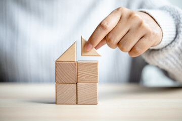 women putting triangle wooden block for show the construction of a wooden in the shape of a house,...