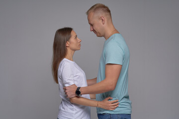 Fototapeta premium Young beautiful couple in love on a white background. Gently hug and kiss. The concept of a happy relationship and love.
