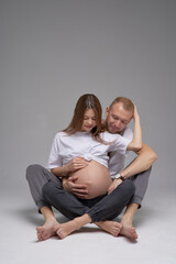 Young beautiful couple in love. The young husband gently hugs his pregnant wife. The concept of a happy family life. Studio photo on white background.
