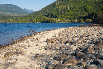 Fototapeta premium Mountain lake surrounded by green pine tree forest in summer. Beautiful lake in the Vancouver Island