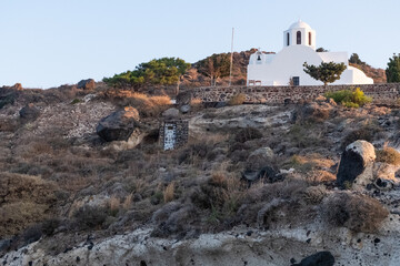 Classic white greek architecture on top of a volcanic stone hill