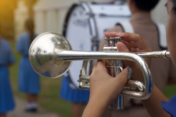 Close-up of student's hand pressing the button of a trumpet to chase a musical note, playing a song...