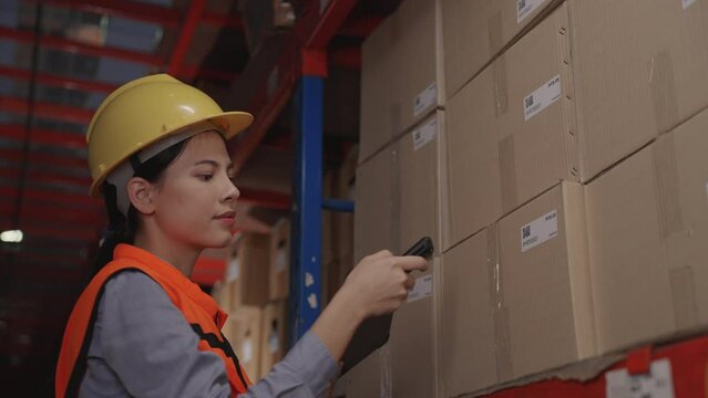 Beautiful woman using tablet and wireless bar code reader reading data on cardboard box on rack or shelf, Warehouse, Logistics, Import, Export, Shipping yard concept.