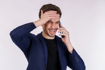 Portrait of tired handsome businessman talking by mobile phone and keeping hand to head isolated over white background