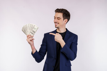 Portrait of a cheerful man pointing finger at bunch of money banknotes over white background