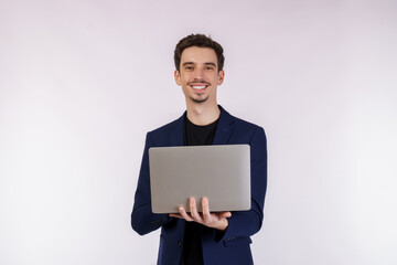 Portrait of young handsome smiling businessman holding laptop in hands, typing and browsing web pages isolated on white background