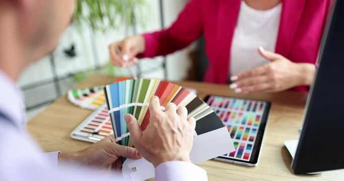 Closeup of hands of architect and customer choosing paint samples for walls