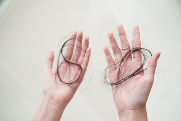 Asian woman have problem with long hair loss attach in her hand.