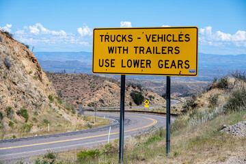 A cautionary sign for trucks and vehicles with trailers to use lower gears while driving down hill