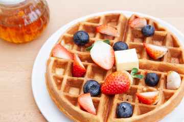 Homemade vanilla waffles with strawberries, blueberries and butter