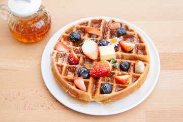 Homemade vanilla waffles with strawberries, blueberries and butter