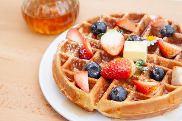 Homemade vanilla waffles with strawberries, blueberries and butter