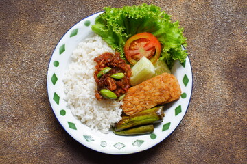 a plate of rice served with sambal and vegetables  