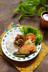 a plate of rice served with sambal and vegetables  