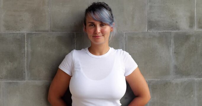 Portrait of beautiful body positive girl with colored hair. She looks straight into the camera and smiles at the end of the clip, and we see orthodontic braces on her teeth.