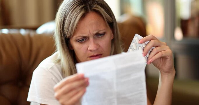 Confused young woman with pills reading instructions for medicine at home