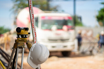 An engineer's leveling camera and white plastic helmet at a construction site in Asia.