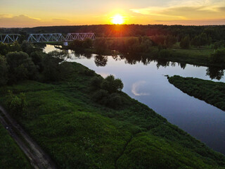 Fototapeta na wymiar Landscape with a railway bridge over the Klyazma river on the background of sunset.