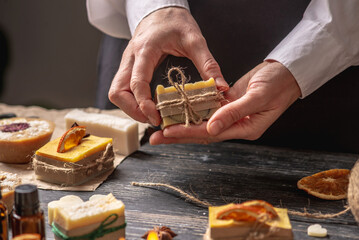 Woman is packing a beautiful natural soap decorated with a slice of orange and a star anise. Process of wrapping presents for New Year and Christmas, festive mood, handmade gifts