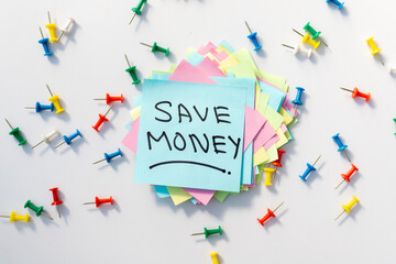 Save Money sticky note with a colorful push pins and white background