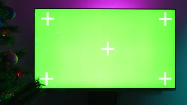 TV With Green Screen Close-up. Led Display With Chroma Key. Glowing Christmas Tree With a Bokeh Lights. New Year Christmas Holidays Concept.