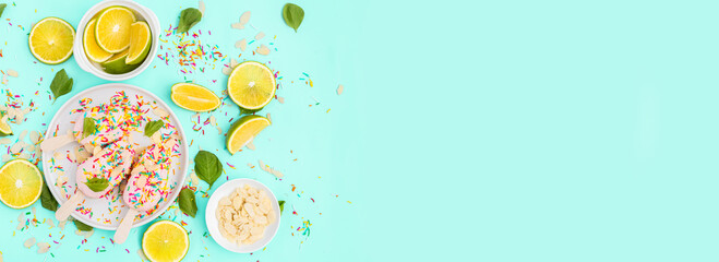 Bright and colorful flat lay of pink strawberry Popsicle ice cream with sliced lime and mint on blue background. Healthy summer food concept. Top view of popsicle with sprinkles, overhead