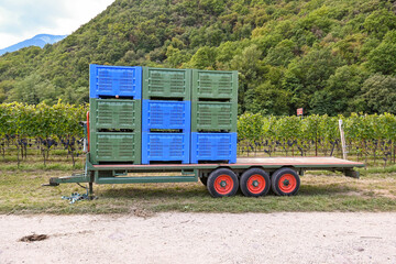 Grüne und blaue Kunststoff-Kisten gestapelt auf einem Anhänger mit drei Reifen vor einer...
